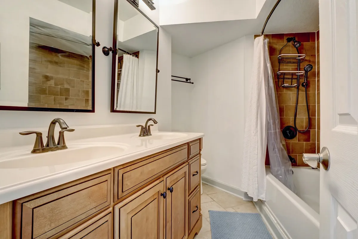 A modern bathroom with a double vanity, mirrors, and a luxurious soaking tub. The setup includes a shower area and is bathed in soft, natural light, creating a calm and serene environment for self-care routines.