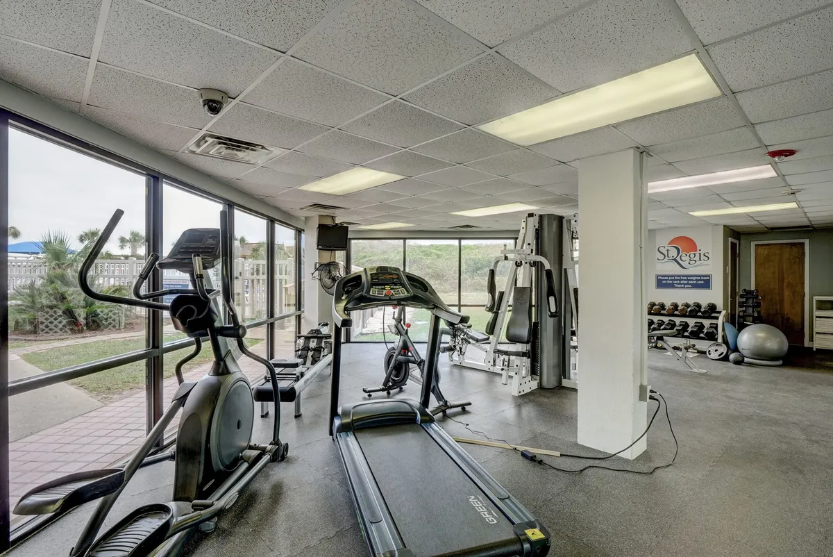 A bright and well-equipped fitness center with treadmills, elliptical machines, weight machines, and expansive windows. The space is inviting for individual workouts or group fitness, with natural light adding energy to the scene.