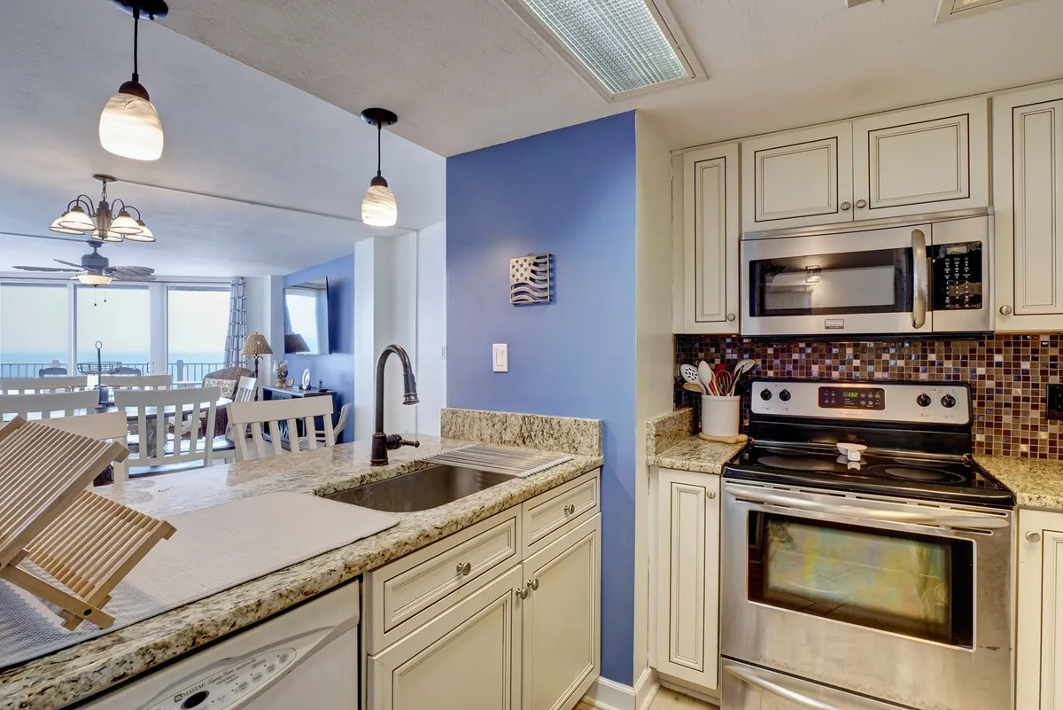 Featuring a granite countertop, stainless steel appliances, blue accent wall, and pendant lighting, this kitchen is designed for both functionality and style. The image shows a relaxed, welcoming environment, suitable for baking, hosting dinners, and casual family moments.