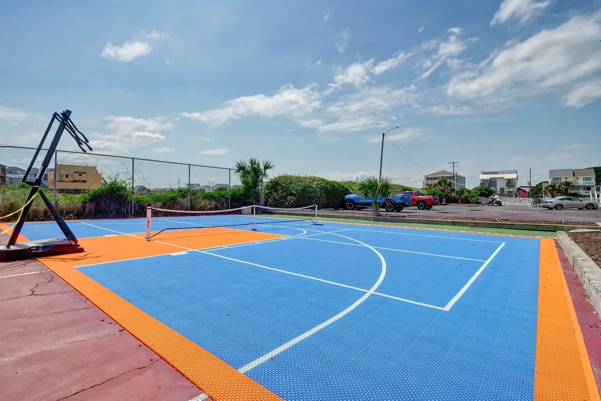 This image features a colorful basketball court with a tennis net, framed by greenery, highlighting spaces designed for active recreation and friendly group competition outdoors.